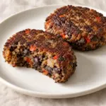 Black bean burgers with browned surfaces and a cut patty showing the bean center.