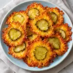 Golden baked cheddar and dill pickle crisps on a pale blue plate