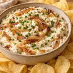 Bowl of creamy cottage cheese caramelized onion dip with chives and chips