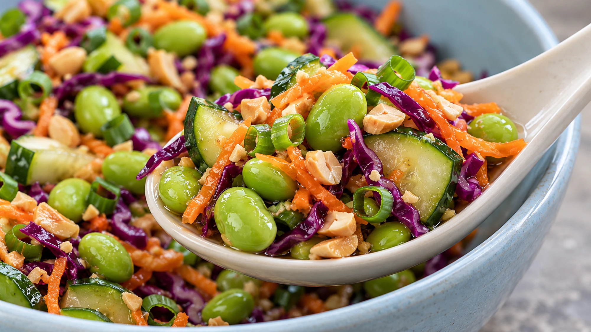 A spoonful of edamame crunch salad showing crisp vegetables, green beans and chopped peanuts.