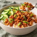 Spoonful of saucy chicken over rice and cucumber in gochujang ground chicken bowls