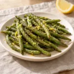 A square photograph of the green beans recipe showing a dressed serving on an ivory plate