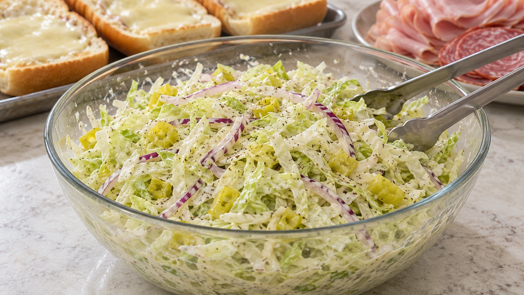 Grinder salad sandwich topping of shredded iceberg, red onion and pepperoncini in a creamy dressing