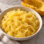 Plain roasted spaghetti squash strands in an ivory bowl.