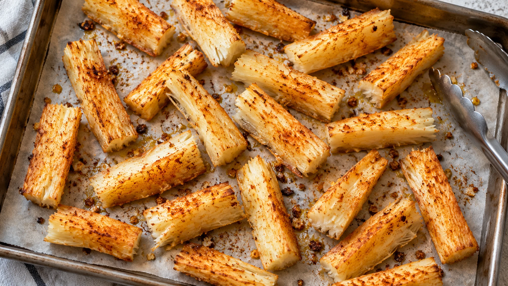 Yuca fries spaced apart on a parchment-lined baking sheet